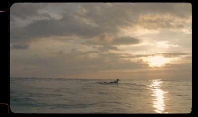 a person riding a surfboard in the ocean at sunset