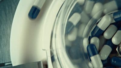 a glass jar filled with blue and white pills