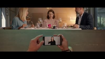 a man taking a picture of a woman sitting at a table