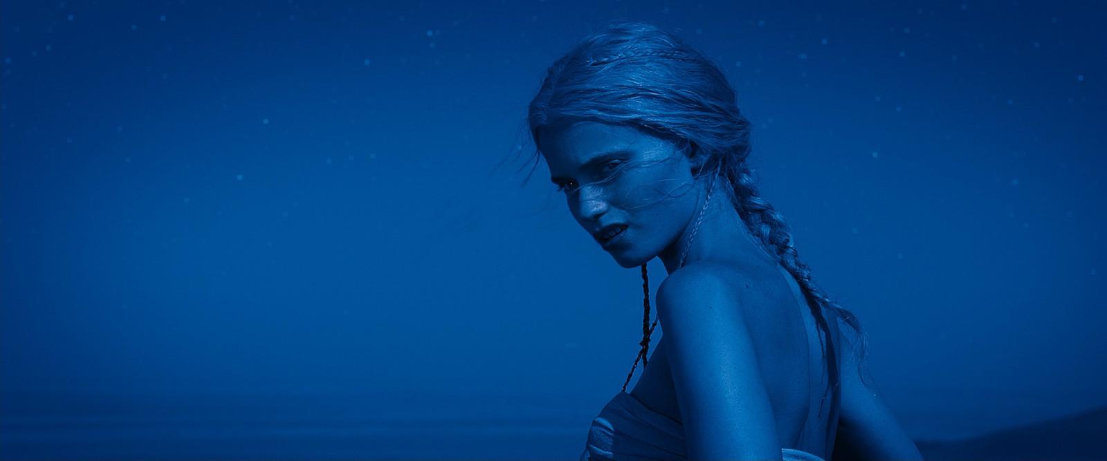 a woman in a blue dress is standing in the rain