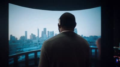 a man standing in front of a window looking at a city