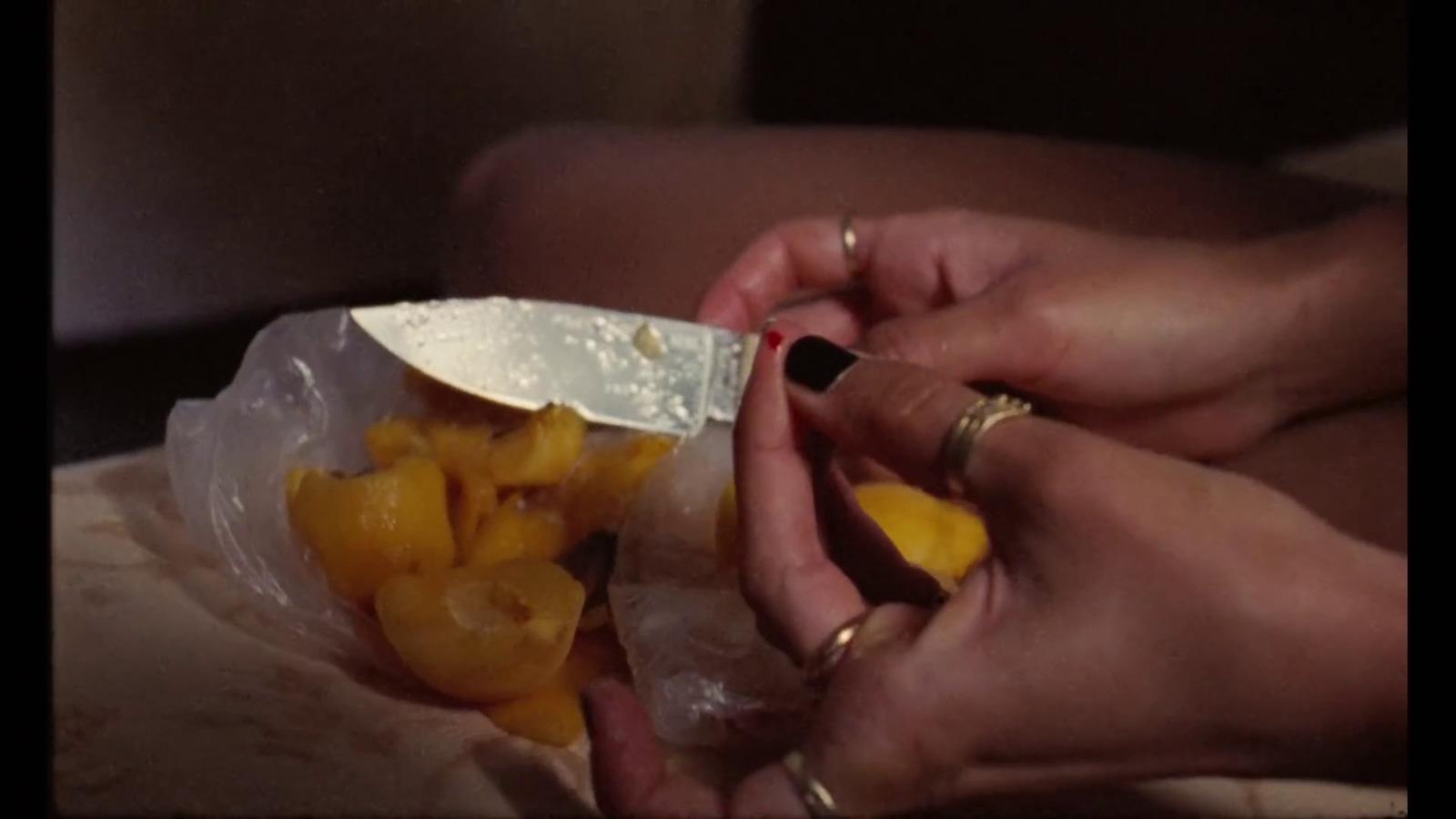 a person holding a knife in a bag of fruit