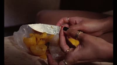 a person holding a knife in a bag of fruit