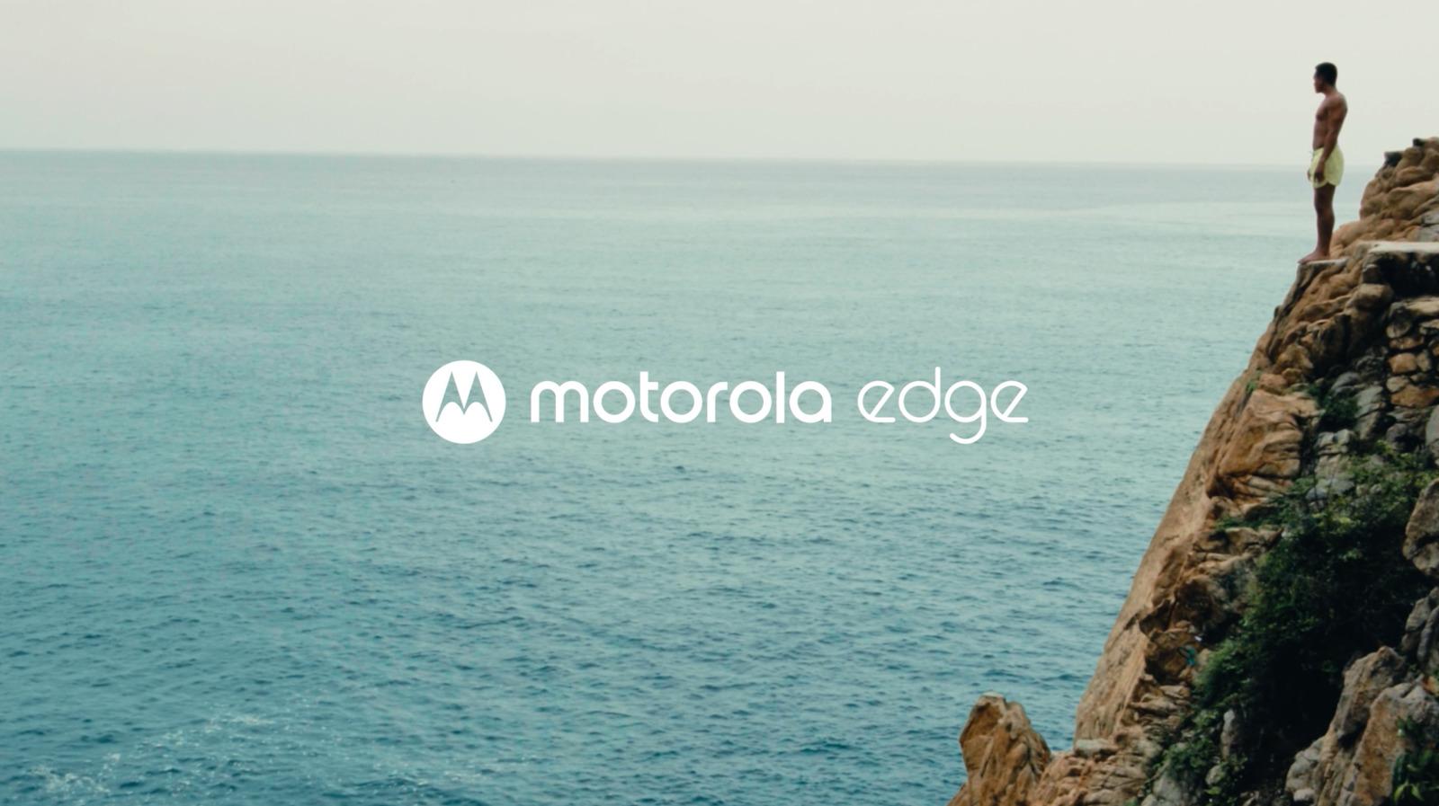 a man standing on top of a cliff next to the ocean