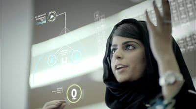 a woman in a headscarf is looking at a screen