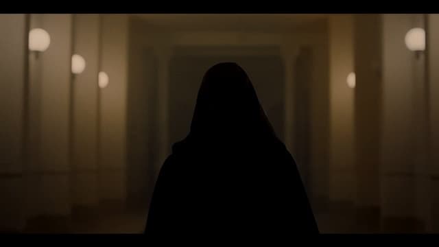 a person standing in a dark hallway with lights on