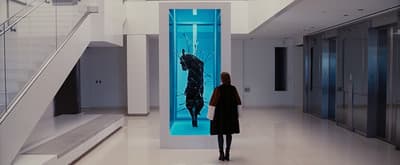 a woman standing in a hallway looking at a painting