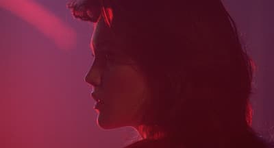 a close up of a woman's face with a red light in the background