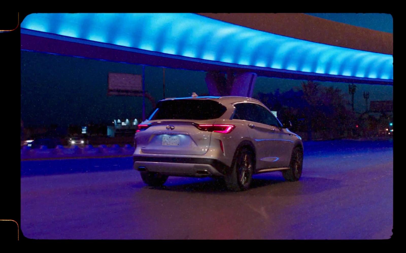 a silver car driving down a street at night