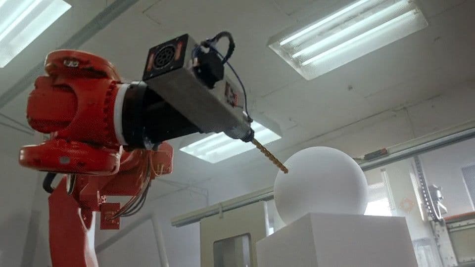 a red robot standing next to a white object