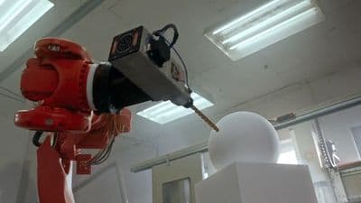 a red robot standing next to a white object