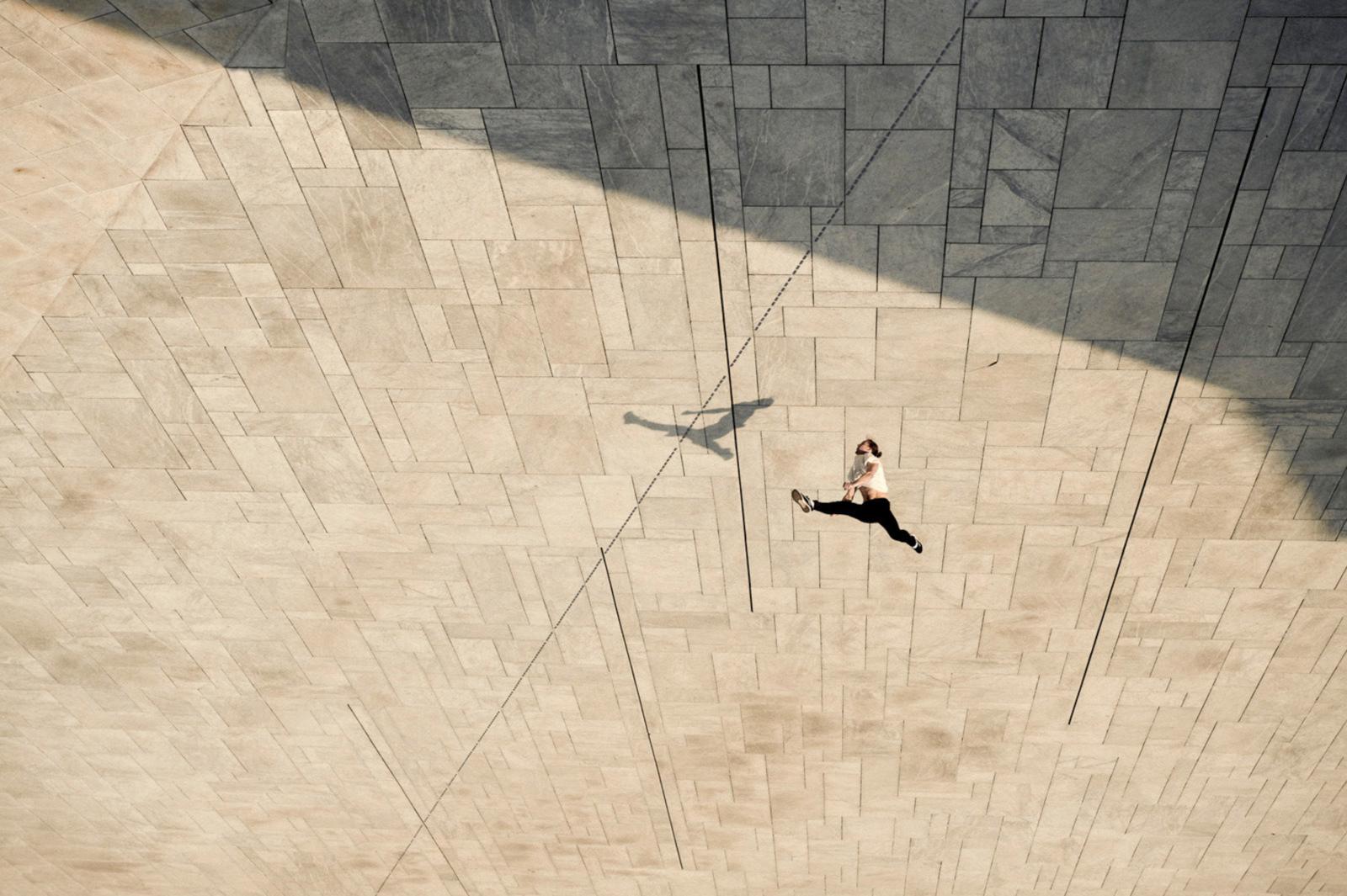 a person walking down a sidewalk next to a wall