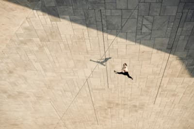 a person walking down a sidewalk next to a wall