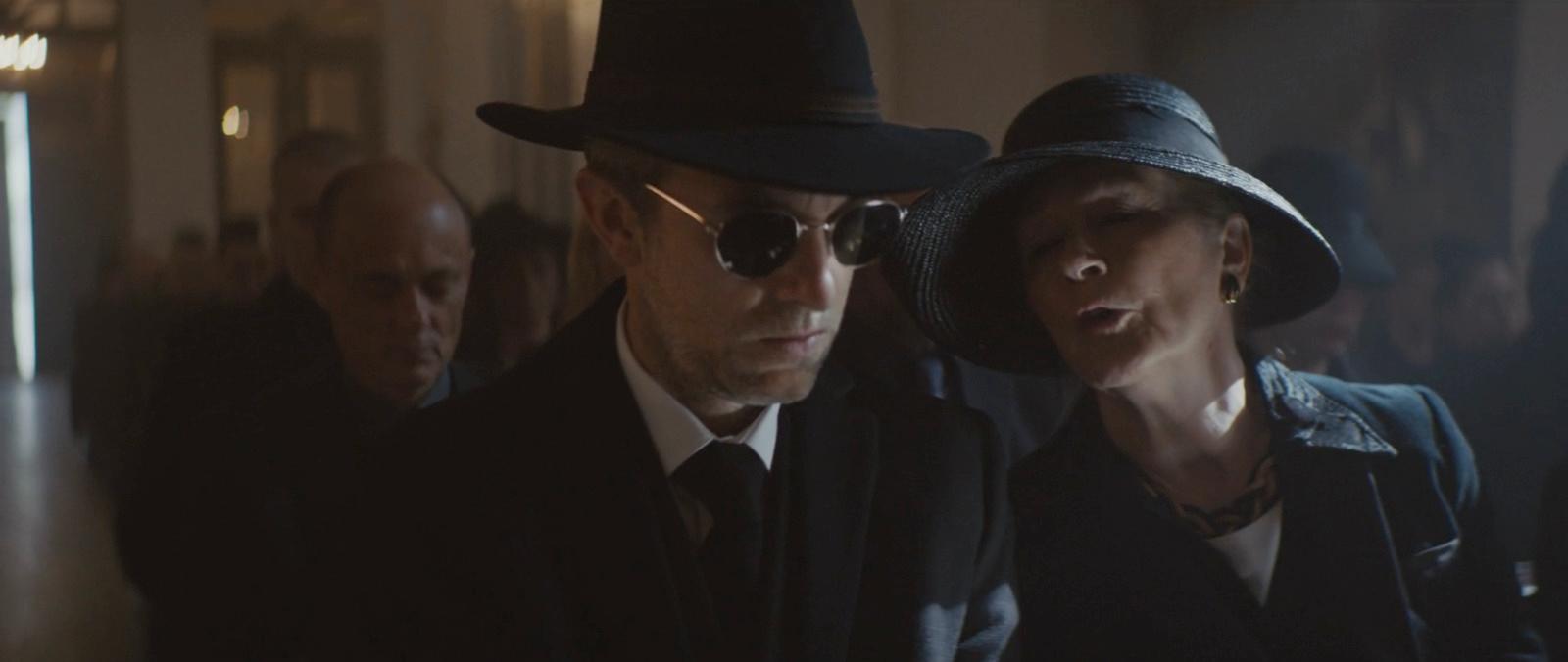 a man in a hat and sunglasses standing next to a woman