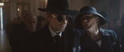a man in a hat and sunglasses standing next to a woman