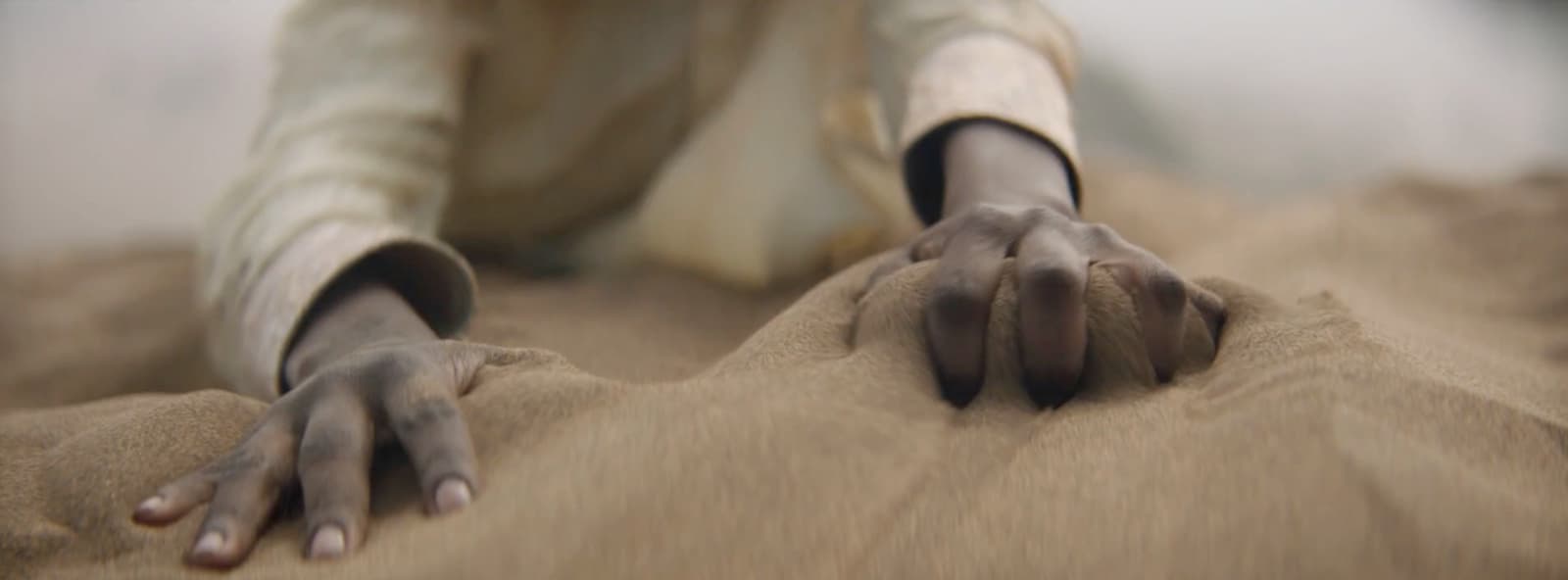 a person laying on the ground with their hands in the sand