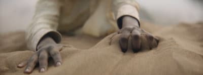 a person laying on the ground with their hands in the sand