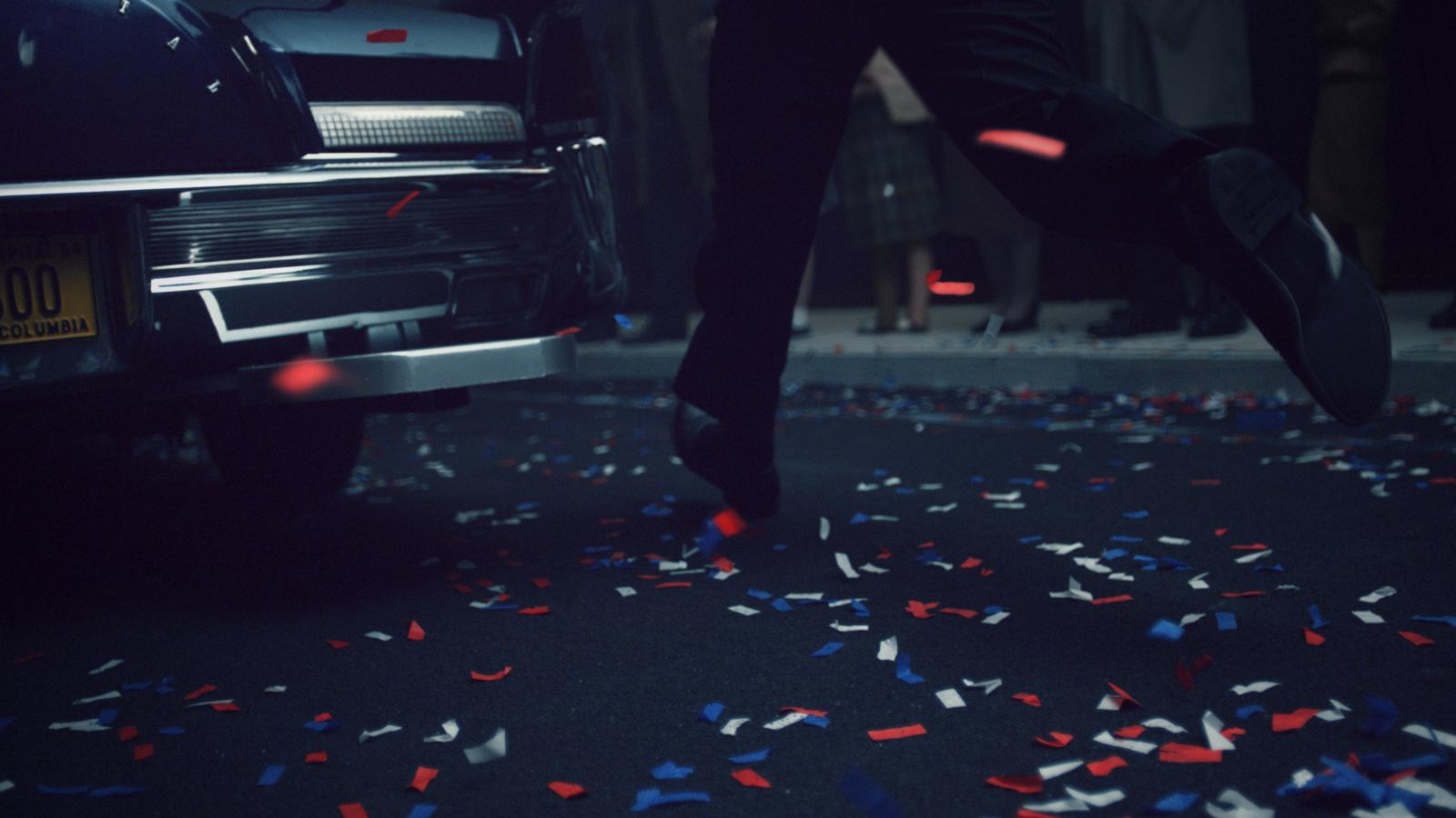 a man is stepping on a car with red, white, and blue confe
