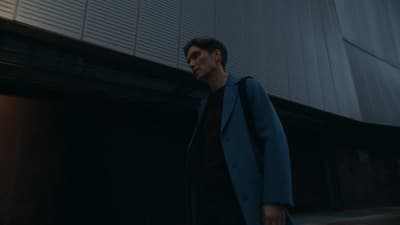 a man in a blue coat walking down a street