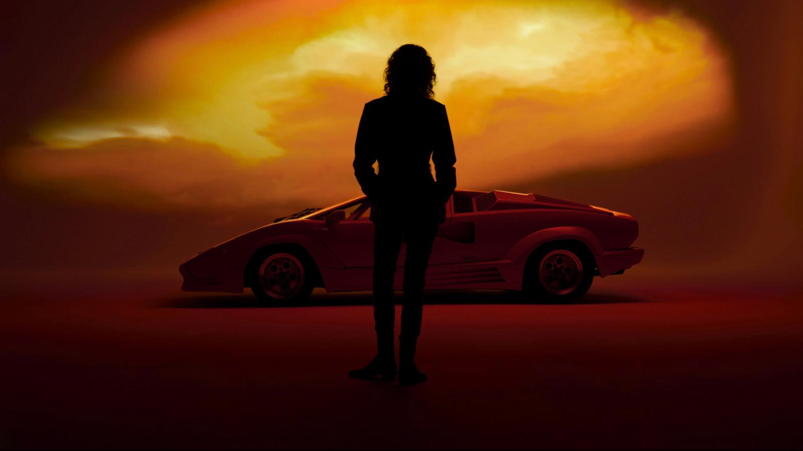 a woman standing in front of a red car