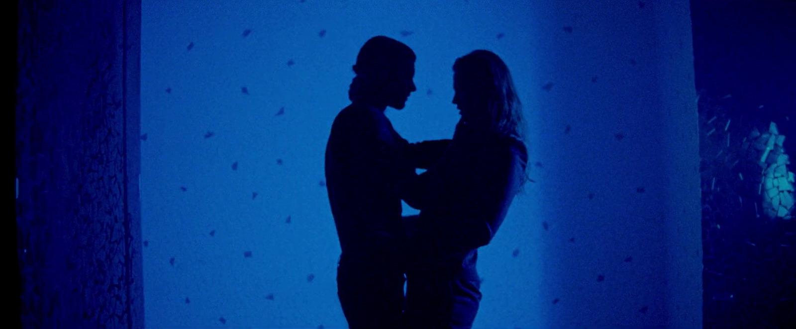 a man and a woman standing in front of a blue wall