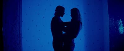 a man and a woman standing in front of a blue wall