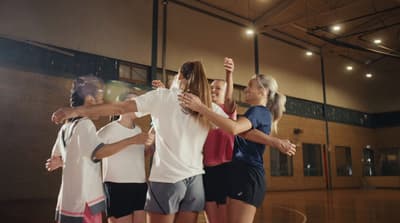 a group of young women standing on top of a basketball court
