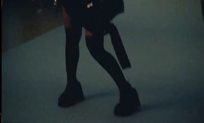 a woman in black boots and a black purse