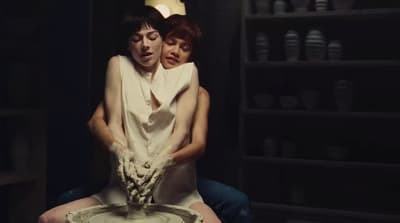 a woman sitting on a man's back in a dark room