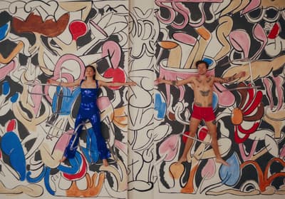 a man and a woman standing in front of a mural