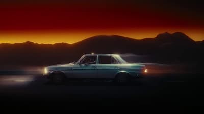 a car driving on a road with mountains in the background