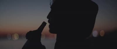 a silhouette of a person holding a bottle in their hand