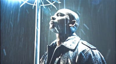 a man standing in the rain with a clock in the background