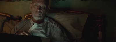 a man sitting on a bed looking at a laptop