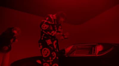a man standing next to a car in a red room