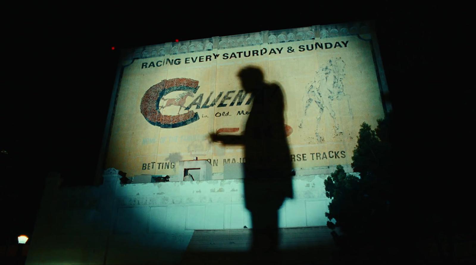 a silhouette of a man standing in front of a sign