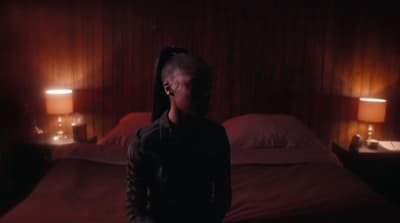 a person standing in a dark room next to a bed
