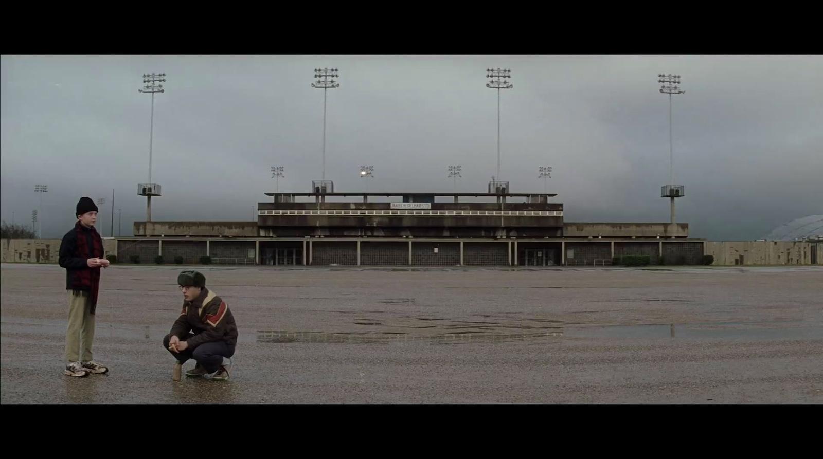 a couple of men standing on top of a wet field
