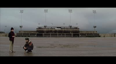 a couple of men standing on top of a wet field