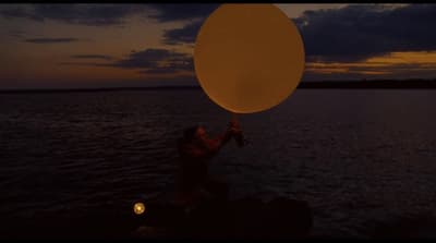 a person holding a large balloon over a body of water