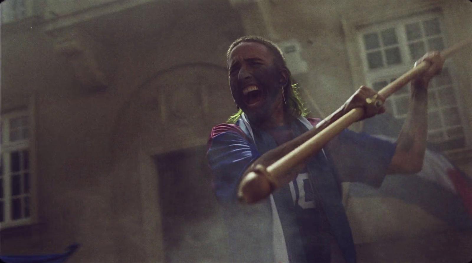 a man holding a baseball bat in front of a building