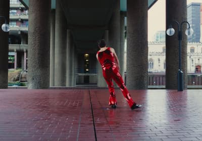 a woman in a red outfit is walking on a brick walkway