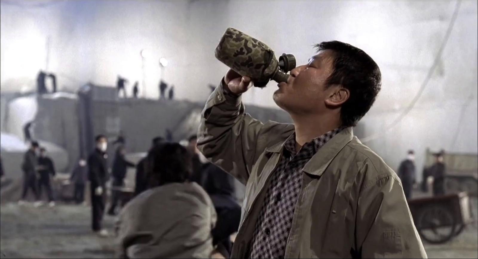 a man drinking from a bottle while standing in front of a group of people
