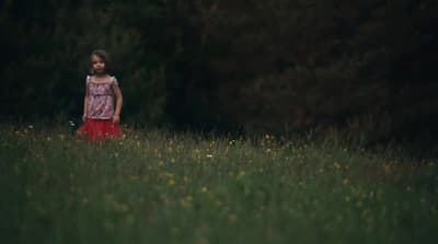 a little girl standing in a field of tall grass