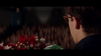a man with glasses looking at a bouquet of flowers
