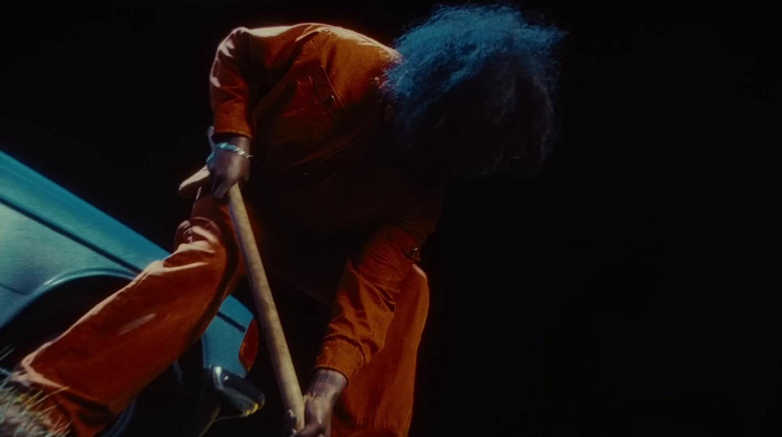 a man with blue hair holding a wooden stick