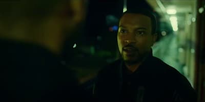 a man in a black jacket talking to another man