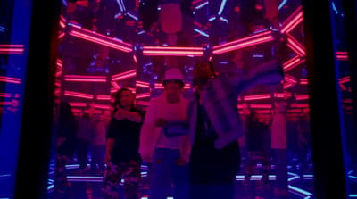 a group of people standing in a room with neon lights