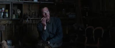 a man sitting in a dark room with his hands on his face