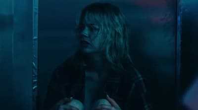 a woman standing in a dark room with her hands on her chest